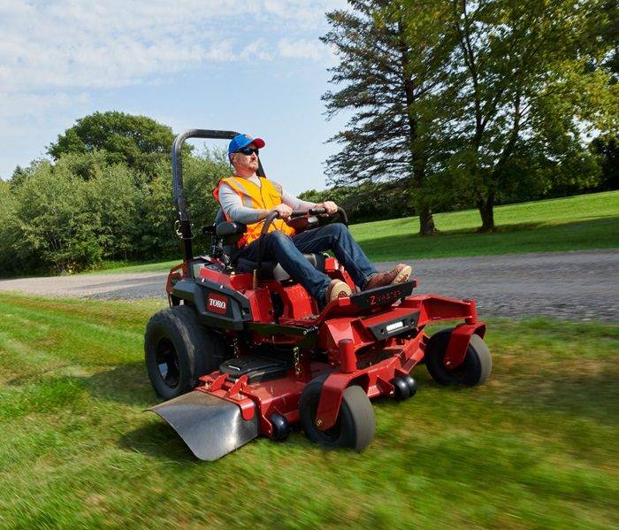 Professional gardener mowing the grass with a riding mower in a residential backyard.