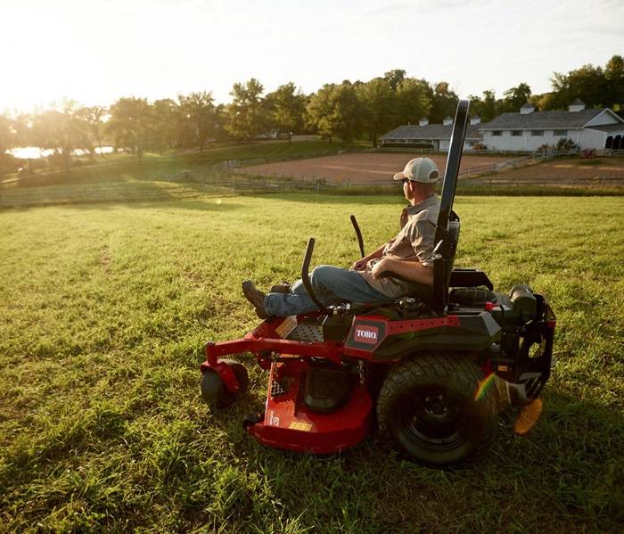 Homeowner mowing his lawn during a bright afternoon with a gas mower.