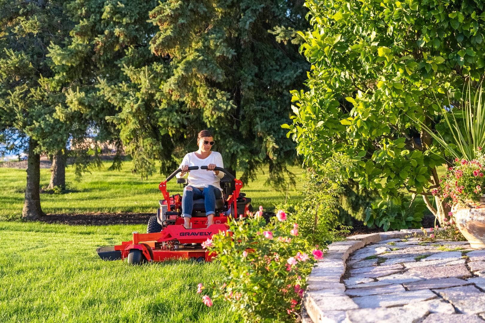 Man navigating a riding mower through complex garden layouts.