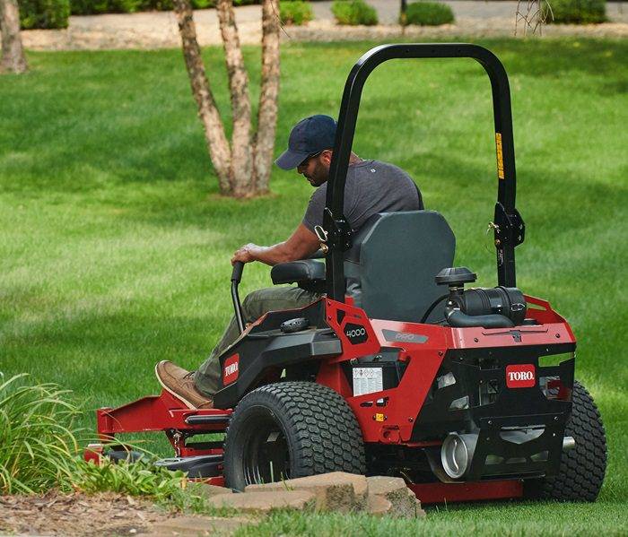 Man performing routine lawn maintenance with a riding mower.