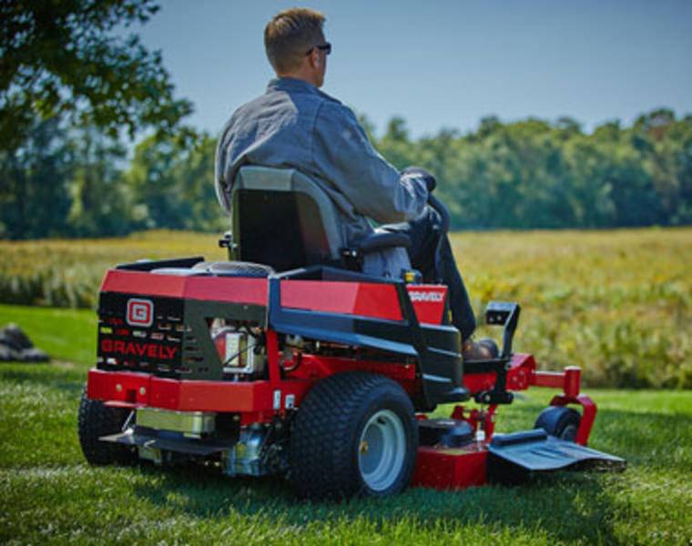 Gentleman mowing large garden area with a high-capacity gas mower.