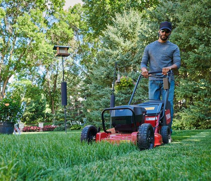 Man trimming the grass with a gas lawn mower.