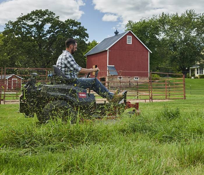 Landscaping professional mowing a well-kept lawn with a riding mower.