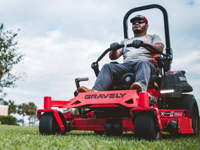 Man using a riding lawn mower in a well-manicured garden.