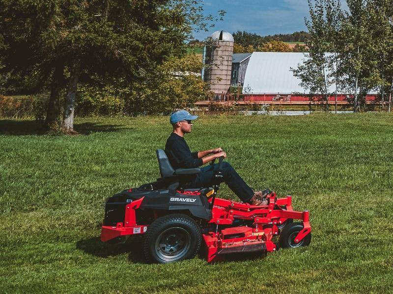 Outdoor maintenance worker riding a mower across a large field.